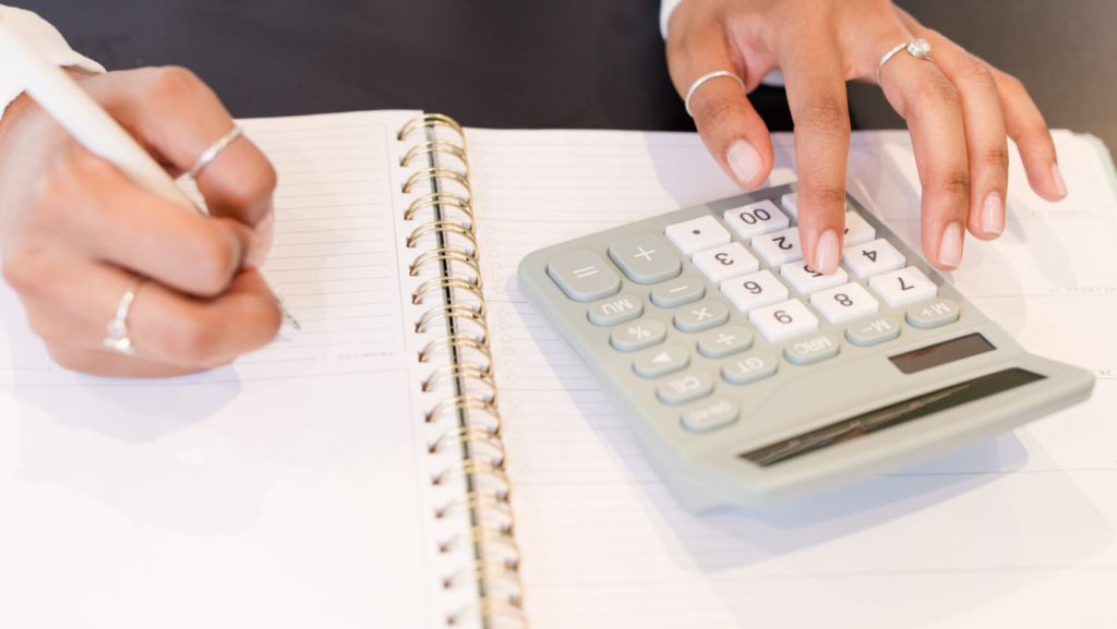 woman uses a gray calculator to determine her budget