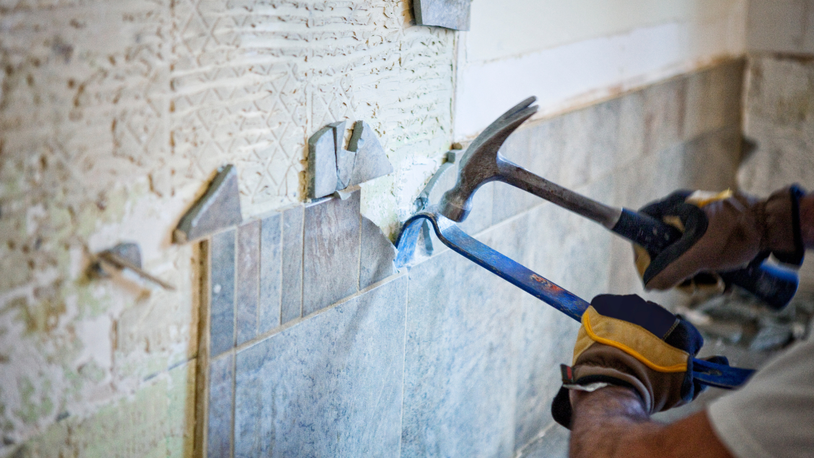 a contractor does demolition on a tile wall